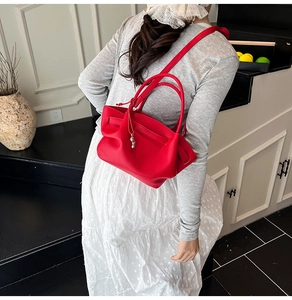 Detail of red pebbled leather bucket bag with side folds and metal lock accessory