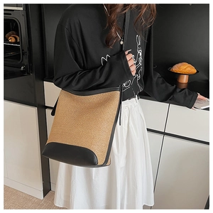 Détails du sac seau en paille avec bordure en cuir noir et texture tressée délicate
