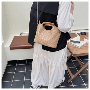 Detail of camel woven leather trapezoid handbag with fixed handles and slim shoulder strap