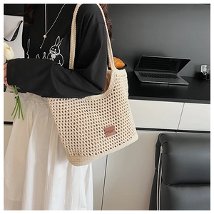 Detail of beige hollow woven tote bag with brown leather label and soft fabric lining