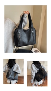Detail of black pebbled leather tote bag with dual zippers and U-shaped metal accent