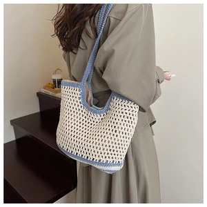 Detailed texture of the hollow crochet knit pattern on the cream and blue shoulder bag