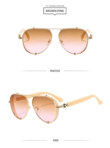 Detail of aviator sunglasses with gold engraved metal frames and brown-pink gradient lenses