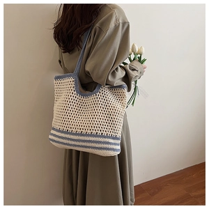 Détail d'un sac cabas en maille beige et bleu avec un grand motif crocheté ajouré chic