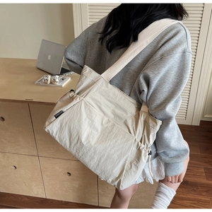 Detail view of large cream canvas tote bag with adjustable drawstring and side label