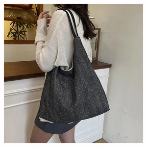 Detailed close-up of dark grey polka dot canvas tote bag texture with black shoulder strap