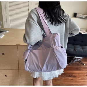 Purple nylon tote bag with drawstring side pockets shown on a model for size scale