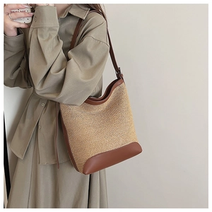 Detail of large woven straw tote bag with brown leather trim and shoulder straps