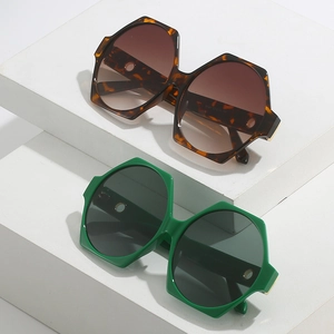 Detail of hexagonal sunglasses in tortoiseshell and green with golden hollow temple tips
