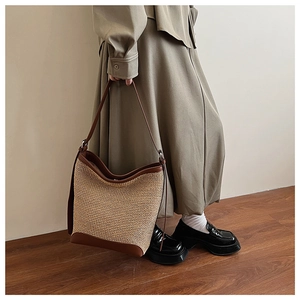 Detail of vintage straw tote bag with brown leather bottom and premium stitched trim