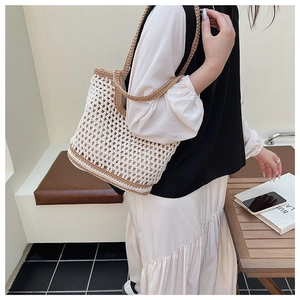 Detail of hollow woven cotton mesh tote bag featuring contrasting brown top handles