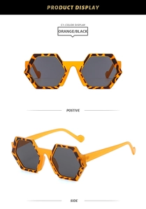 Detailed view of hexagonal orange and black tortoiseshell sunglasses with dark gray lenses