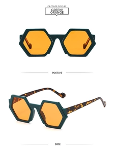 Detailed view of hexagonal sunglasses with dark green frames and bright orange lenses