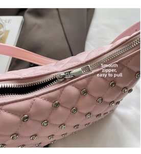 Close-up of smooth silver metal zipper on pink quilted crossbody bag with studs