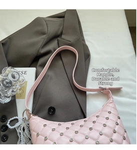 Detail of pink quilted hobo bag with silver studs and chain on a stylist's desk