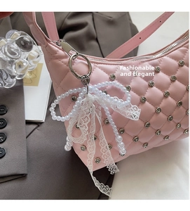 Detail of pink quilted handbag with silver studs and a pearl lace bow charm
