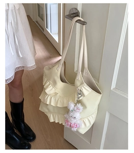 Detailed view of cream tote bag with layered lace ruffles and a plush bunny charm