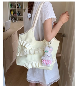 Detail of cream nylon tote bag with ruffled layers and white plush bunny charm