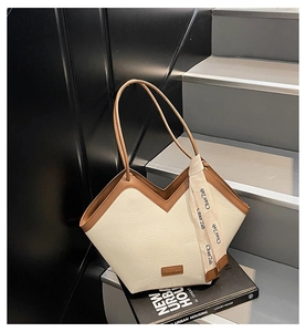 Detail of vintage cream tote bag with brown trim and decorative scarf on a book