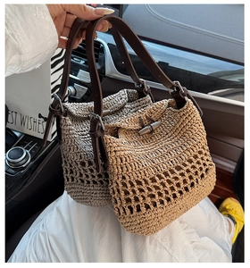 Detail of woven straw tote bag featuring a leather strap and horn toggle closure