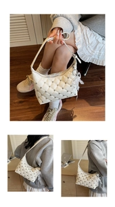Detail of white quilted handbag featuring silver rhinestones and a pearl lace charm