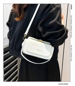 Detail view of the white crossbody bag featuring elegant gold hardware and brand lettering