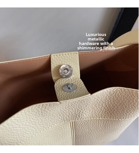 Detailed close-up of magnetic buckle closure on cream lychee grain leather handbag