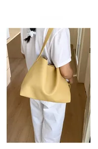 Grande borsa tote gialla in pelle indossata da una modella in un interno minimalista