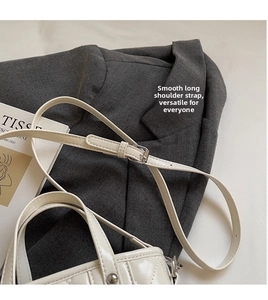 Close-up of white quilted patent leather bag showing smooth adjustable shoulder strap