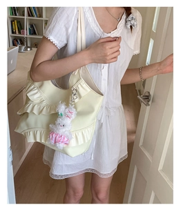 Detail view of light yellow ruffled tote bag with a cute plush rabbit charm on strap