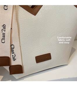 Detail of cream pleated leather tote with brown accents and branded canvas handle