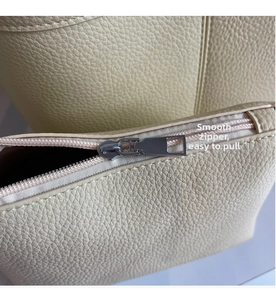 Close-up of smooth silver metal zipper on a beige lychee pattern leather handbag