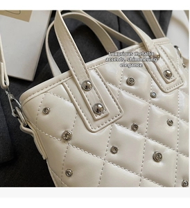 Detail of quilted leather bucket bag with silver rivets and sparkling crystal studs