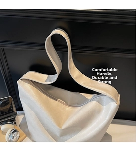Detail of a large cream tote bag featuring pebbled leather texture and metal zipper