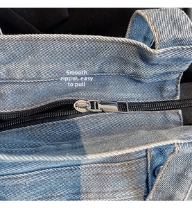 Detail of smooth silver metal zipper on light blue denim canvas shoulder bag