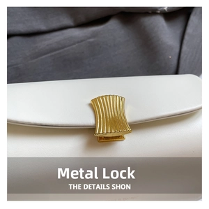 Detailed macro view of the fan-shaped gold metal lock and leather texture on a white bag