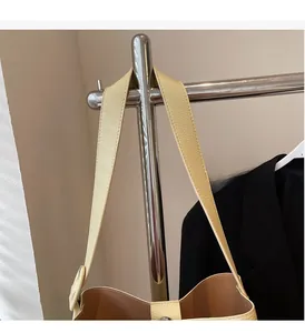 Detail of lychee pattern leather handbag strap hanging on a silver metal stand