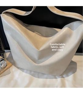 Detailed macro view of the cream white PU leather texture and shoulder strap on a tote bag