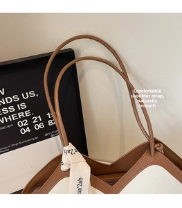 Close-up of contrast brown leather strap and textured off-white tote bag stitching