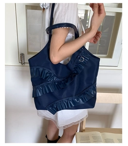 Detail of navy blue tote bag with tiered ruffle accents and nylon texture shown on shoulder