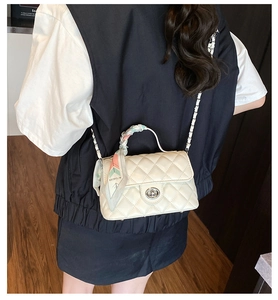 Detail of white quilted chain bag with patterned silk scarf handle and silver twist lock
