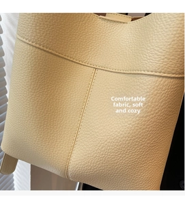 Detail of cream pebbled leather texture and precise stitching on fashion bucket bag