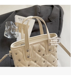 Detailed view of cream quilted bucket bag featuring silver rivet studs and a sturdy handle