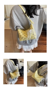 Detail of yellow quilted underarm bag with lace bow, pearl charm and rhinestone accents
