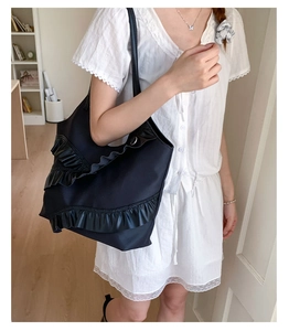 Detail of black large tote bag featuring triple-layered ruffles and thin shoulder straps