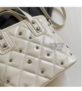 Close-up of cream quilted bucket bag with diamond stitching and silver metal studs
