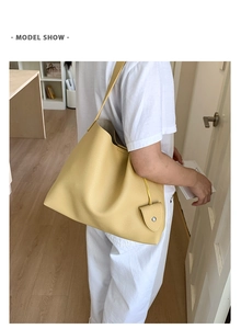 Dettaglio della borsa tote gialla in pelle martellata con mini ciondolo decorativo