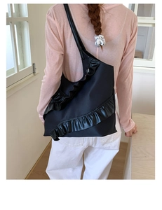 Detailed view of black tote bag with ruffled leather edges worn over the shoulder