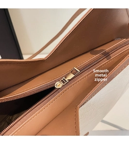 Detail of the smooth golden metal zipper and stitching on the caramel leather tote bag