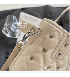 Detail of silver metal D-ring and hook on cream quilted bucket bag with studs